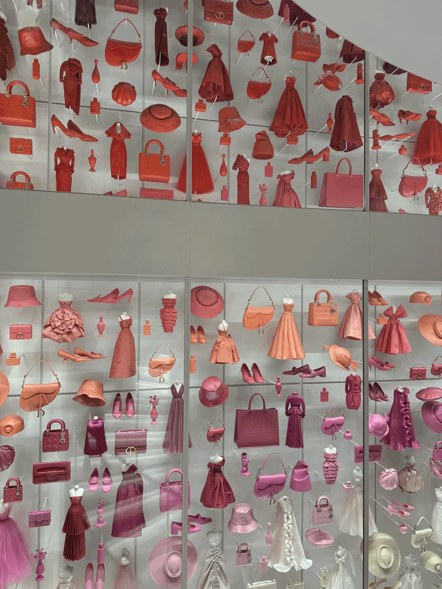 A wall of Dior bags, shoes, hats, and dresses arranged in shades of red and pink